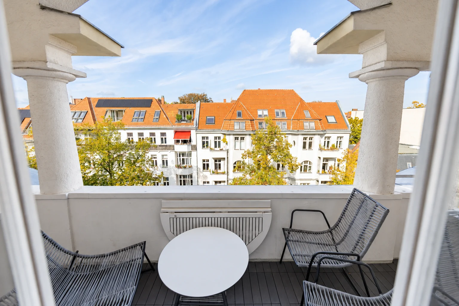 Der überdachte Säulenbalkon mit Blick auf die Dächer und Baumkronen in Friedenau