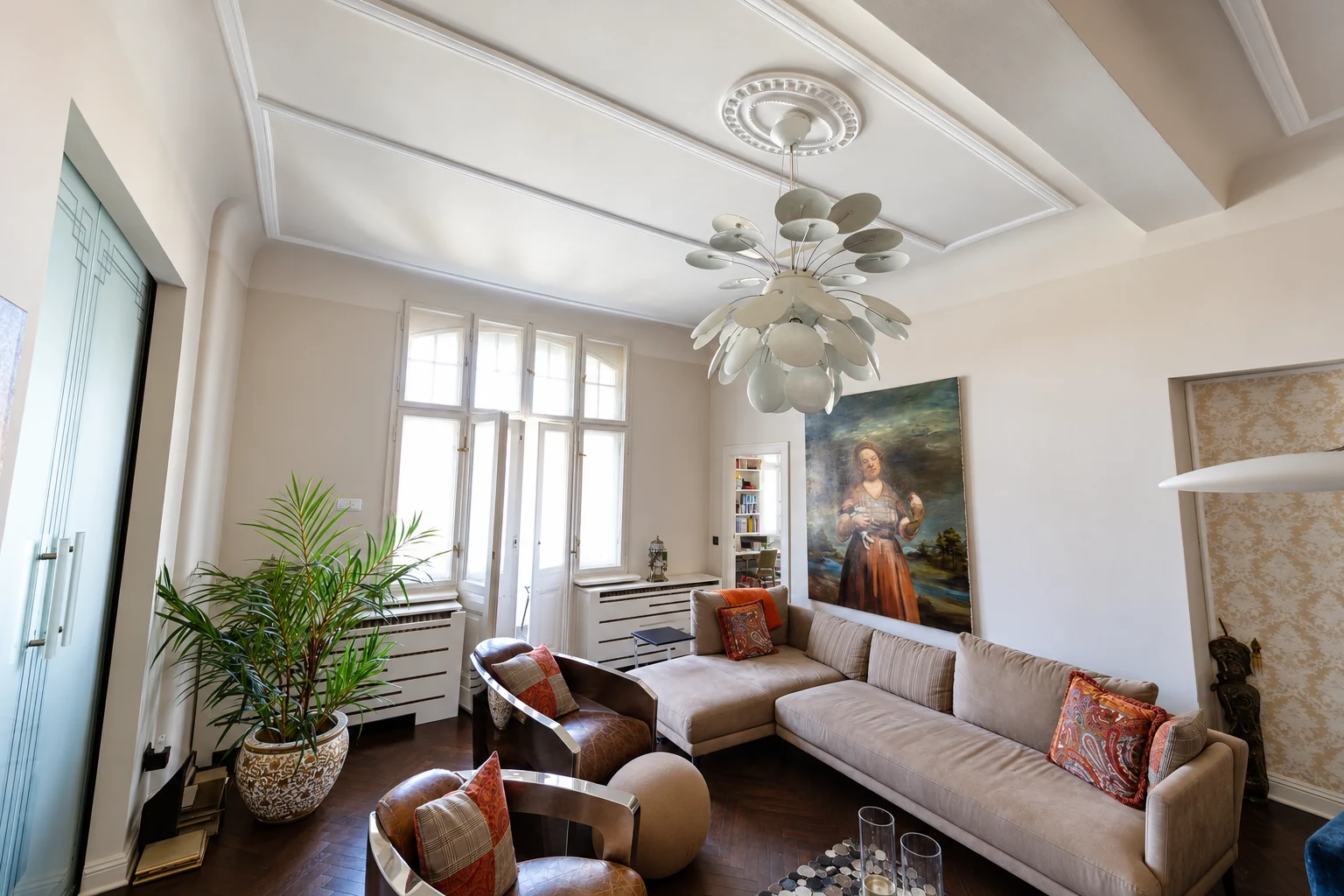 Großzügiges Wohnzimmer mit hohen Stuckdecken, dunklem Holzboden und Balkonzugang